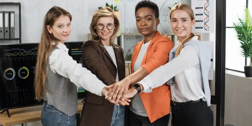four-happy-multiracial-female-partners-stacking-th-2023-11-27-05-11-39-utc